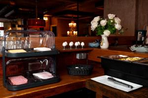 a restaurant with a counter with food and flowers at Hotel The Stamp in Den Bosch