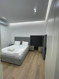 a white bedroom with a bed and wooden floors at Vila Elezi 2 in Tirana +36 photos