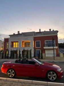 a red car parked in front of a house at Lux Studio Lustica Bay and Car in Luštica