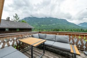 a couch on a balcony with a table and mountains at Stanglhof - by myNests in Bad Aussee