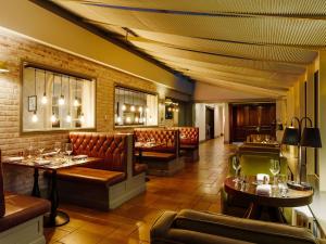 a restaurant with couches and tables and chairs at Mercure Haydock Hotel in Haydock