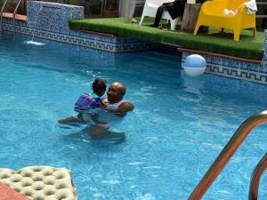 a man holding a child in a swimming pool at Epa's Place in Awoyaya