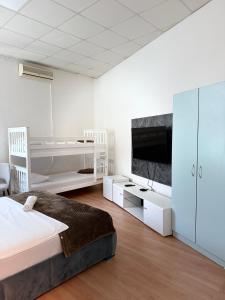 a white bedroom with a bed and a tv at Hostel Nikšić in Nikšić