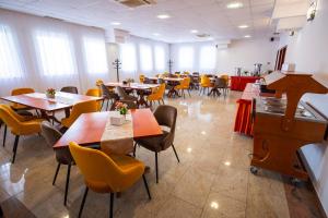 a dining room with tables and yellow chairs at Vila Aura in Sovata