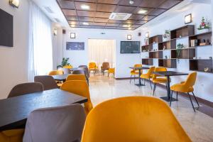 a waiting room with tables and yellow chairs at Vila Aura in Sovata