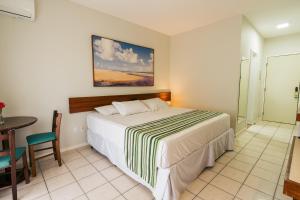 a hotel room with a bed and a table and a table at Resort Costa Dos Coqueiros in Imbassai