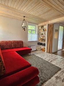 a living room with a red couch and a window at Namiņš AMRAI in Ventspils +14 photos