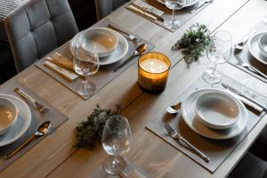 a wooden table with plates and wine glasses on it at Chalet Ruka Aurelius in Ruka +22 photos