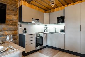 a kitchen with white cabinets and a wooden wall at Chalet Ruka Aurelius in Ruka