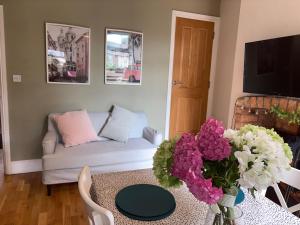 a living room with a couch and a table with flowers at Central Derby pride park 4 bedrooms 7 beds -Spacious contractors large group -Cul de Sac EasyFREE PARKING in Derby