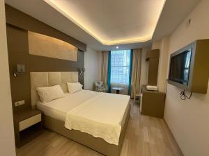 a hotel room with a bed and a television at Ayseli Hotel in Mersin