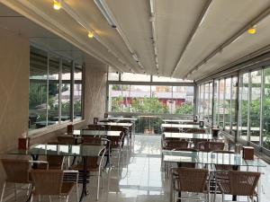 a dining room with tables and chairs and windows at Ayseli Hotel in Mersin