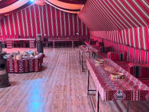 a red room with tables and chairs in it at Mujib Castle Gate Camp in Dhībān
