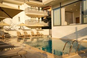 a swimming pool with chairs and umbrellas next to a building at AViSOS HOTEL & APARTMENTS in Marmaris