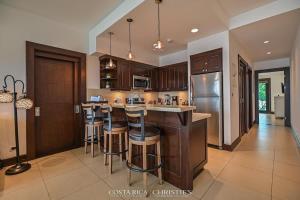 a kitchen with wooden cabinets and a island with bar stools at 360 Splendor 306-Ocean View Condo-Breakfast in Playa Flamingo