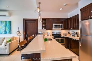 a kitchen with wooden cabinets and a large counter top at 360 Splendor 306-Ocean View Condo-Breakfast in Playa Flamingo