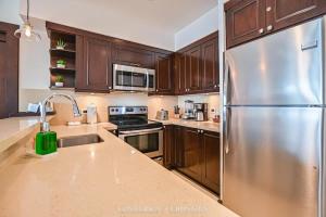 a kitchen with wooden cabinets and a stainless steel refrigerator at 360 Splendor 306-Ocean View Condo-Breakfast in Playa Flamingo