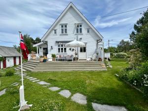 ein weißes Haus mit einer Flagge im Garten in der Unterkunft Lenes hus in Halden