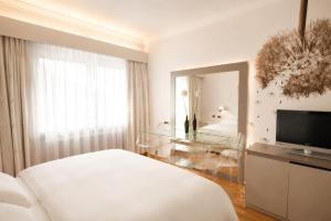 ein weißes Schlafzimmer mit Bett und Spiegel in der Unterkunft Hotel Aurora in Meran