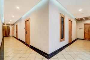 a corridor with white walls and wooden doors at Hotel O by OYO REFRESH INN & SUITES in Kozhikode