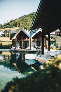 a house on the water next to a lake at ROHO MURAU Hotel Rosenhof Murau in Murau