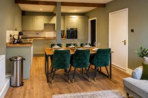 a kitchen with a wooden table and green chairs at The Castle City Centre Apartment in Canterbury