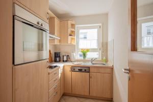 a kitchen with wooden cabinets and a sink and a window at Ferienwohnung Sonnenfreuden direkt am See, ideal für Paare in Überlingen