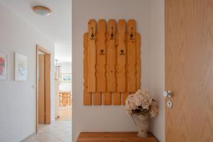 a hallway with a vase of flowers and a wall with wooden panels at Ferienwohnung Sonnenfreuden direkt am See, ideal für Paare in Überlingen +4 photos