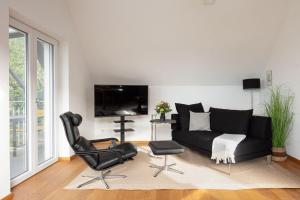 a living room with a black couch and a chair at Studio Süßenmühle mit viel Privatsphäre, direkt am Naturbadestrand in Sipplingen
