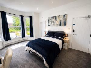 a white bedroom with a large bed and two windows at The Carlton Collection in Birkenhead