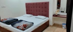 a small bed with a red headboard in a room at Hotel Touchwood in Prayagraj