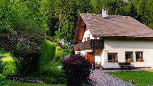 a small white house with a bench in a yard at Hiša nasproti sonca in Kranjska Gora