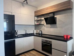 a kitchen with black and white cabinets and a sink at The Touch of the Sea in Durrës