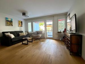 a living room with a couch and a tv at Apartmenthaus Gauenpark - CharmingStay in Flumserberg
