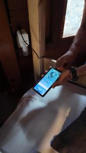 a person holding a cell phone on a bed at Raiz Hostel in Jericoacoara