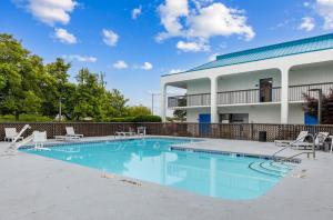 a swimming pool with chairs and a building at Studio 6 Suites Jacksonville, NC - Camp LeJeune in Jacksonville