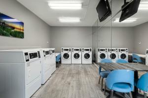 a laundry room with washing machines and a table and chairs at Studio 6 Suites Jacksonville, NC - Camp LeJeune in Jacksonville
