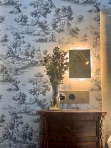 a vase of flowers on a table with a wallpaper at Hotel Europa Boutique Sevilla in Seville