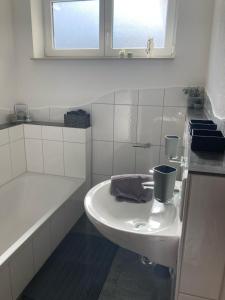 a white bathroom with a sink and a bath tub at Lieblingsplatz in Pfullendorf +13 photos