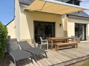 a patio with a table and chairs and a wooden table at Le cocon de Jules et Chloé in Cléder