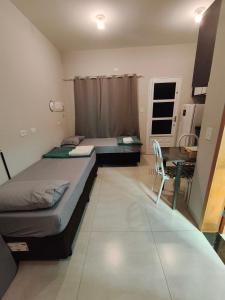 two beds in a room with a table and a desk at Yama Hospedagem e Moradia in Paranavaí