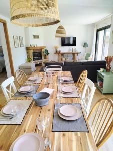 a long wooden table with plates and glasses on it at Le cocon de Jules et Chloé in Cléder