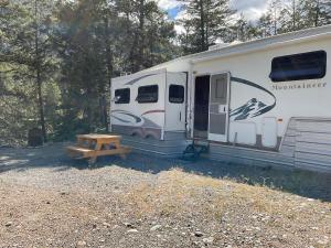 a white trailer with a wooden bench next to it at Doug's Emporium and Riverside Cabins in Hedley +48 photos