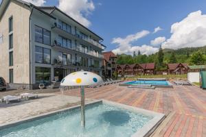 a hotel with a pool with a umbrella in the water at Хатинка у Румуна in Tatariv +144 photos