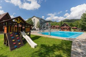a swimming pool with a slide and a playground at Хатинка у Румуна in Tatariv