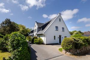 a white house with a black roof and a driveway at Meersalz in Tinnum