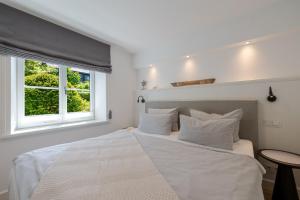 a bedroom with a large white bed with a window at Meersalz in Tinnum