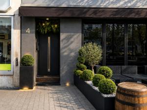 a front door of a store with a table and bushes at La Suite Hotel - Self Check-in in Hanau am Main