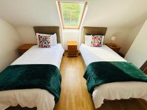 two twin beds in a small room with a window at Slieve League House B&B in Teelin