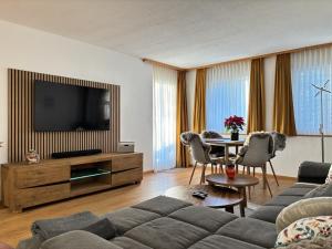 a living room with a couch and a television at BergSee Apartament Laax in Laax